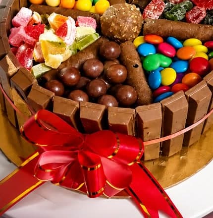 KitKat fence cake loaded with gems, chocolates and dry fruits with red ribbon